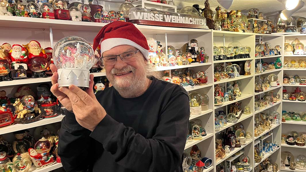Josef Kardinal posing with his snow globes collection