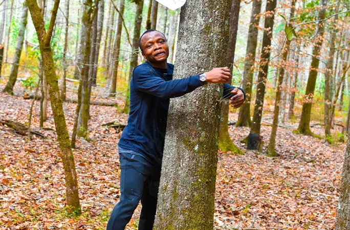 Abubakar hugging a tree and smiling