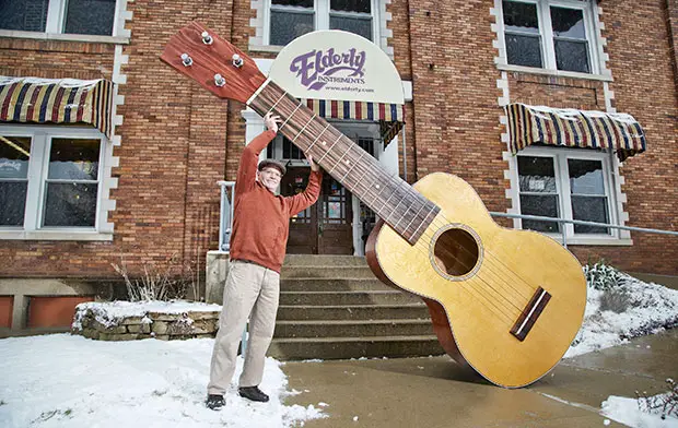 Holding up the largest ukulele
