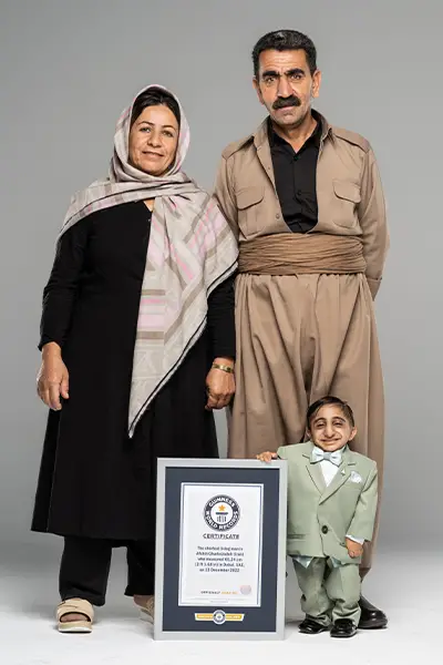 Worlds shortest man standing with his parents and Guinness World Records certificate