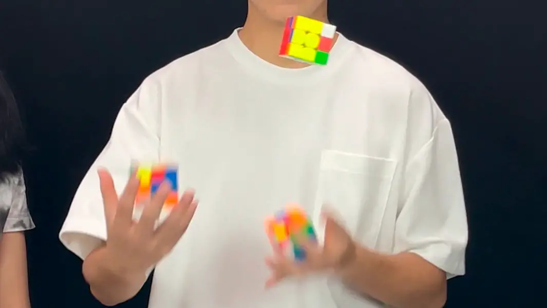 Three puzzle cubes juggled and solved simultaneously to break record