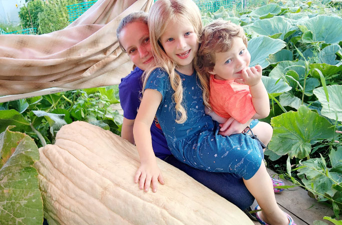 Derek's children sitting on thre squash