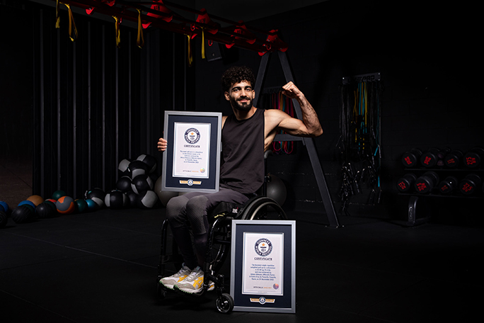 Adnan on wheelchair with certificates