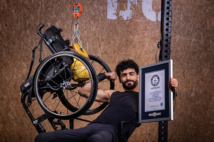Adnan smiling with wheelchair and cert