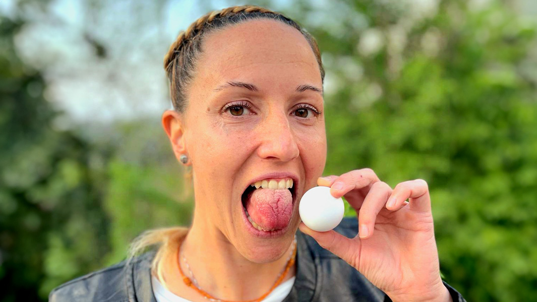 Spit image of Ambra holding a ping pong ball next to her tongue and having it measured