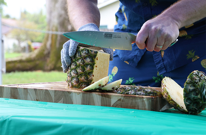 Close up of Rich's hands as he cuts pineapple