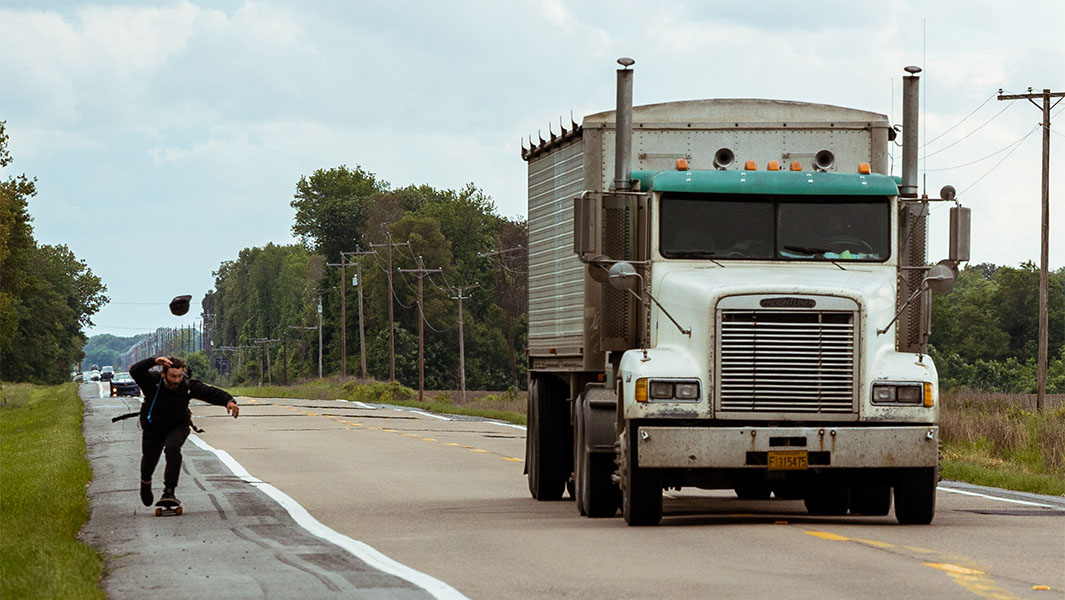 Chad Caruso skateboards next to a truck on his trip across America