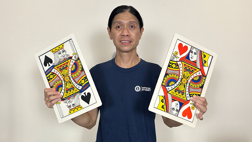 A close up of Avery Chin holding giant playing cards