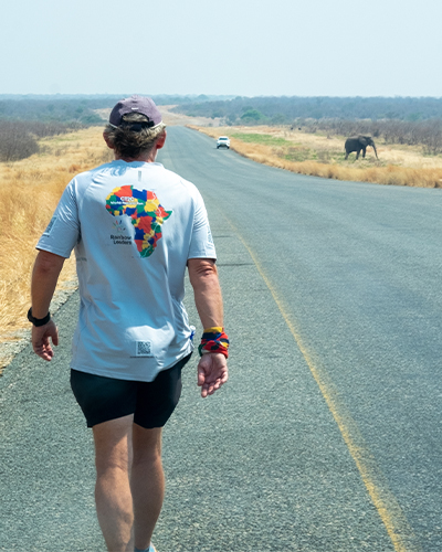 Keith walking down a road with elephant in the distance