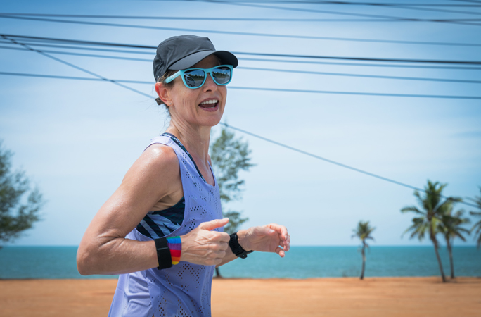 Natalie Dau smiles to the camera as she runs with her sunglasses on