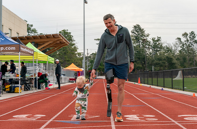 Adam holding his sons hand on the track