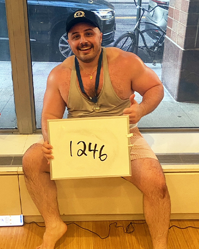 Alex smiling while holding a whiteboard reading 1246