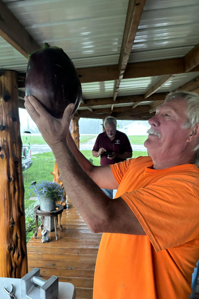 Dave Bennett proudly lifting up the heaviest eggplant after weighing