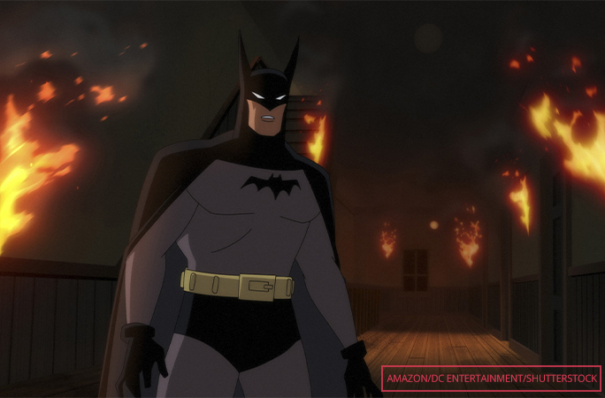 Batman standing in front of a burning building