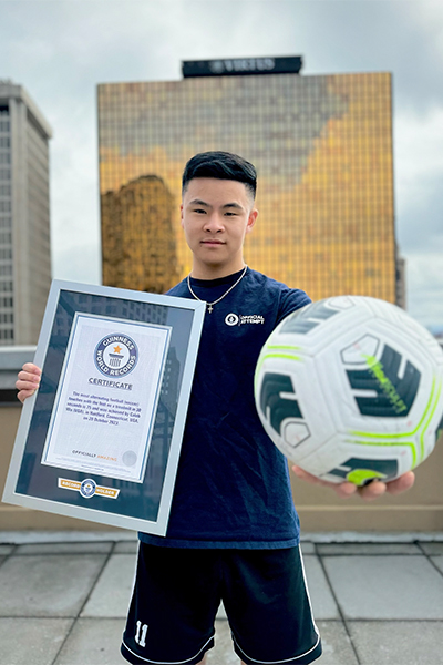 Caleb holding his certificate and a football