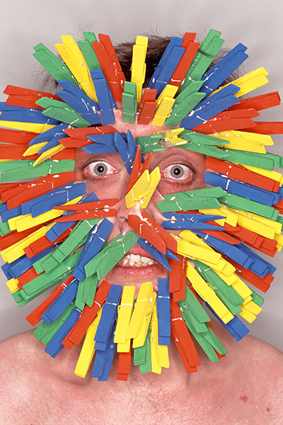 Garry Turner with lots of clothes pegs clipped on his face