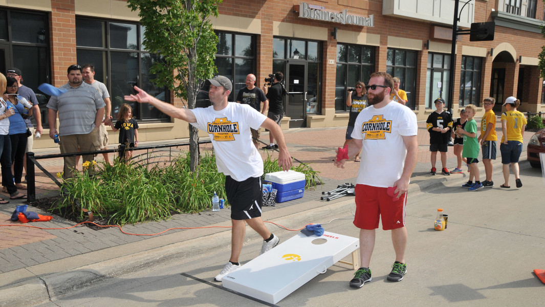 A teammate throws a bag into a cornhole