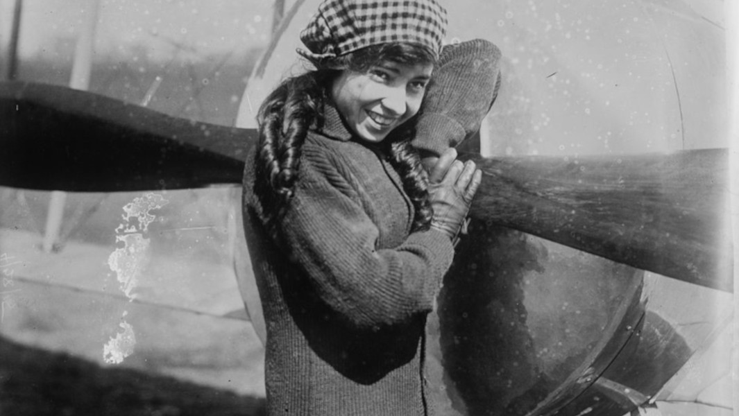 Katherine Stinson smiling with her airplane in 1915
