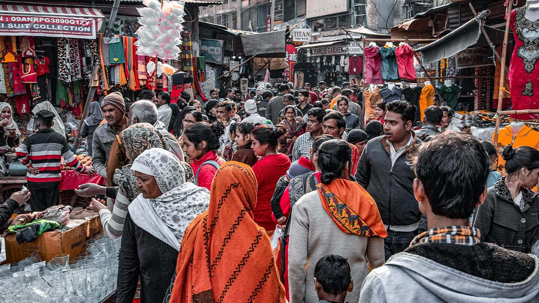 A bustling scene at a market in India with lots of people shopping at stalls
