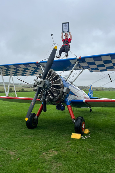 John on top of the plane with his certificate