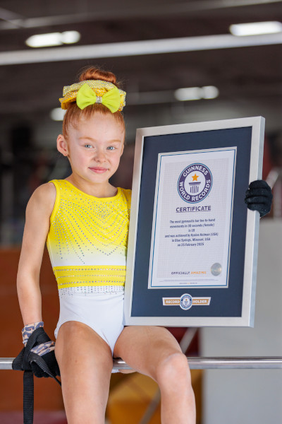 Kynlee sitting on the bar holding her GWR certificate