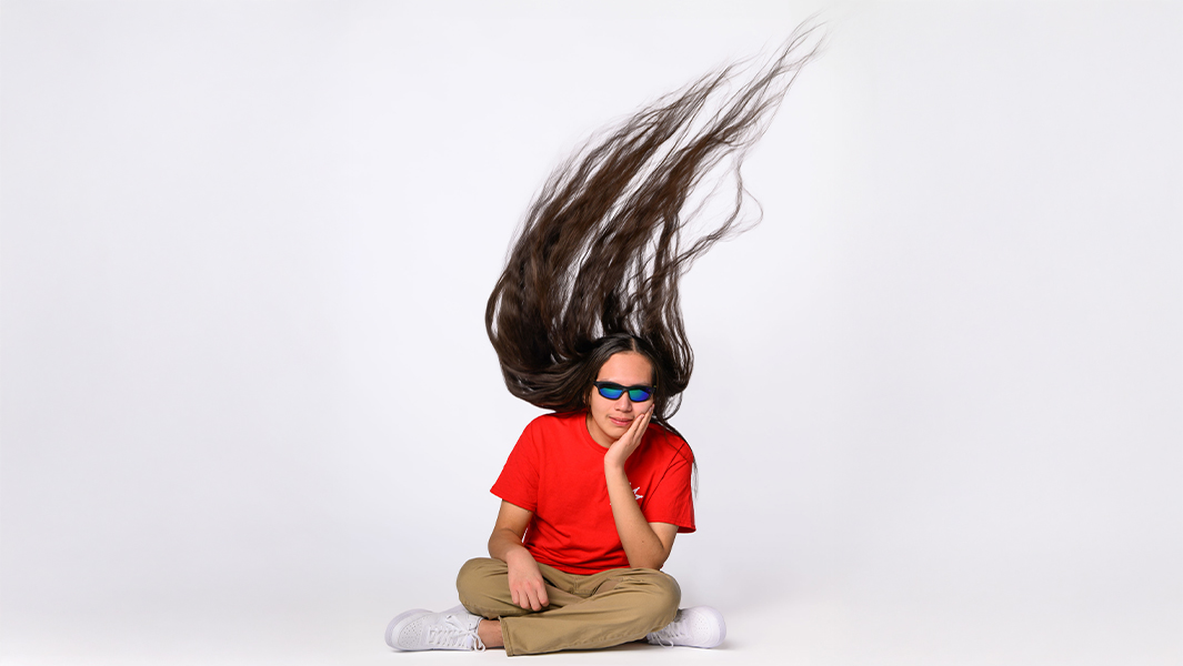 split image of Reuben with his hair hanging loose, lying on the floor and holding it in his hands