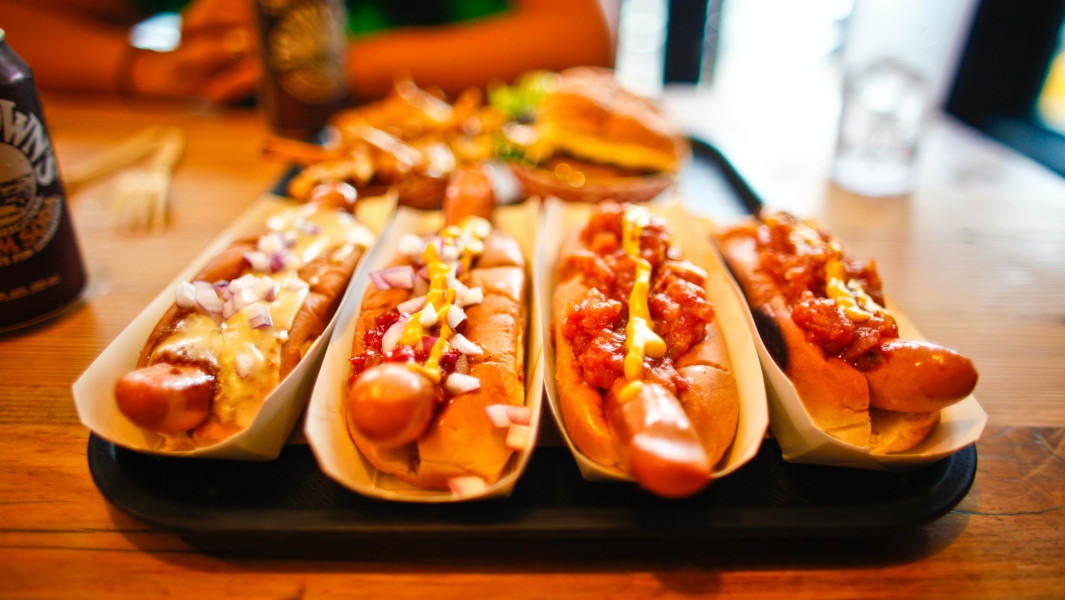 Generic image of hot dogs on a wooden table. Photo credit: Caleb Oquendo/ Pexels.