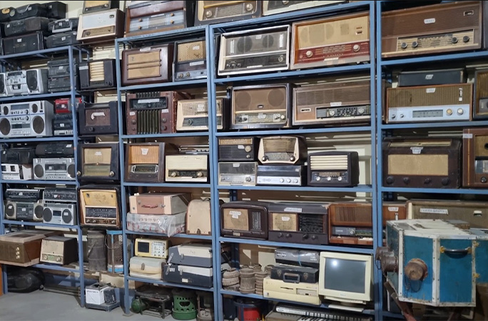 A wall full of radios on shelves