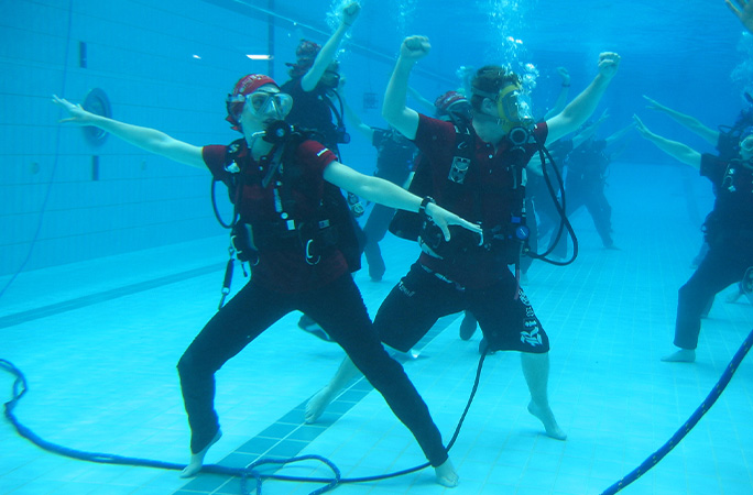 Dancers in scuba gear posing underwater