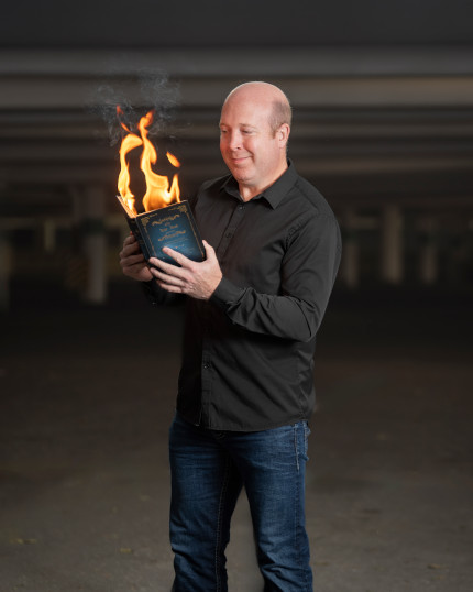 Ian looking at a book that is on fire. 