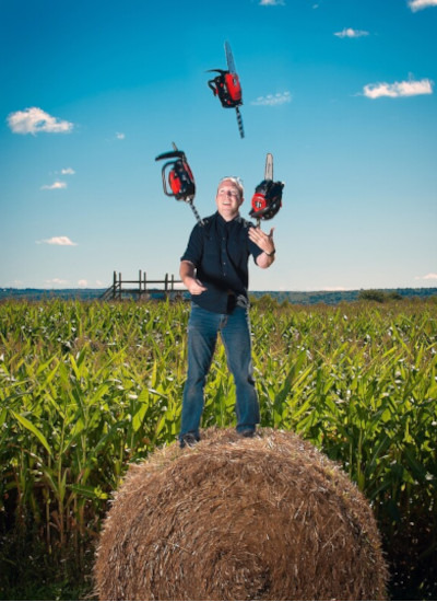 Ian juggling chainsaws while standing on hay. 