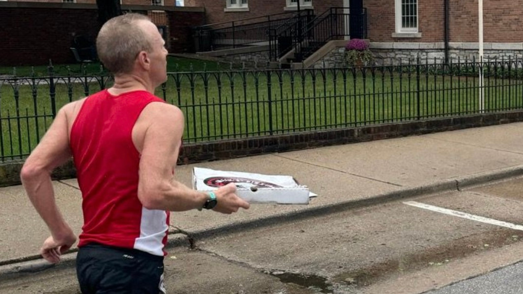 Mike Cole holding a pizza while running