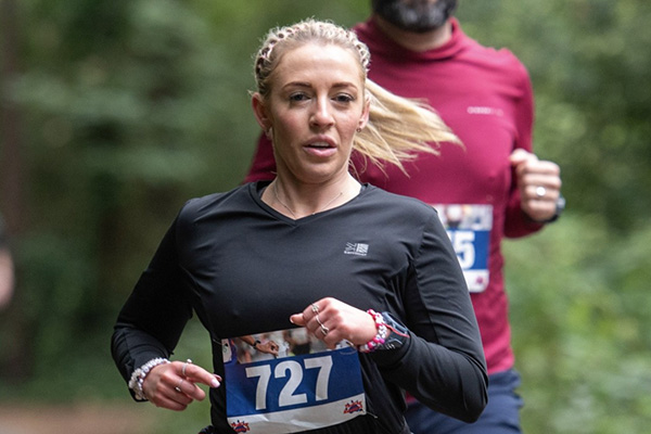 Rebecca running in a forest during a marathon