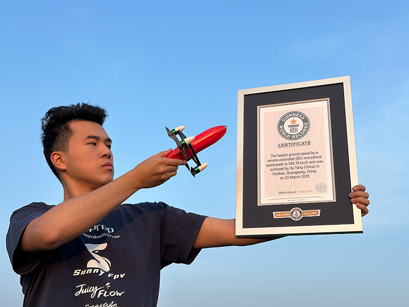 xu yang holding remote controlled microdrone quadcopter pointing to GWR certificate