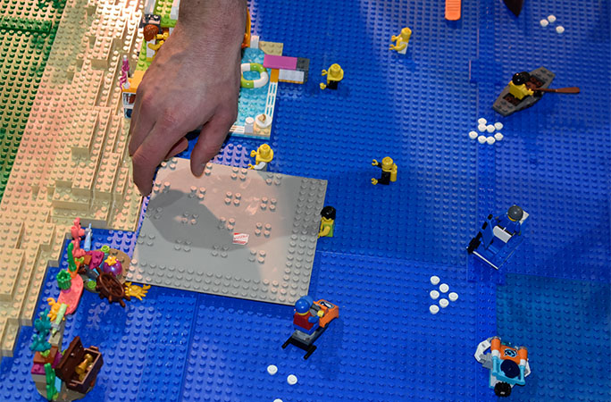 hand reaching in to build the LEGO diorama