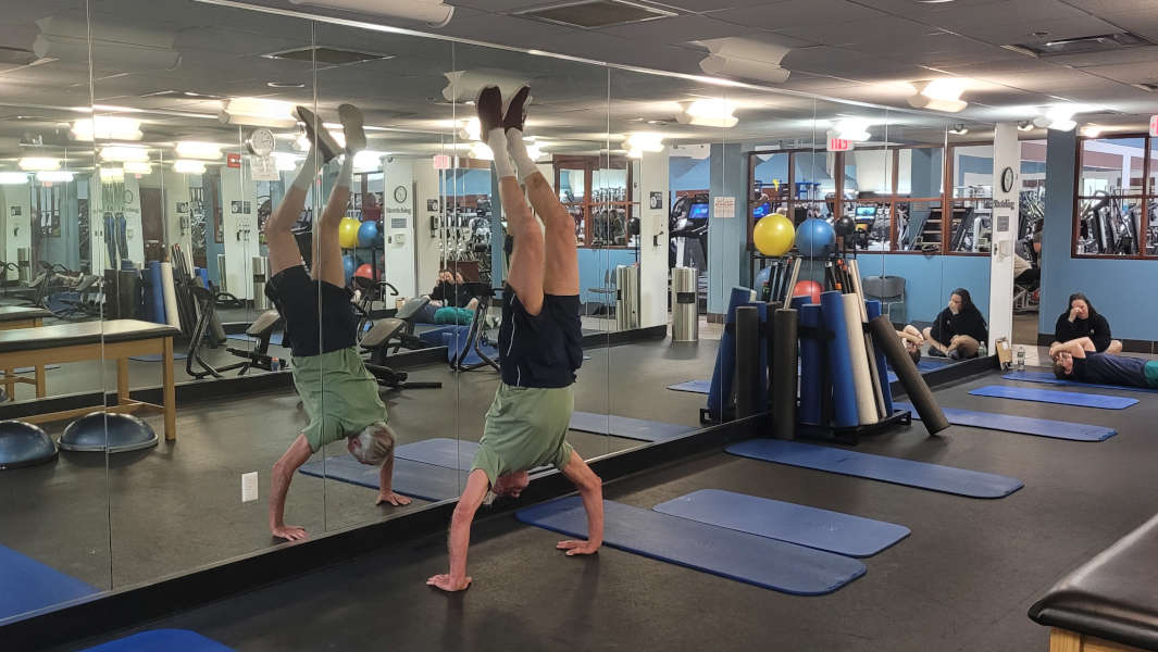 Paul doing a handstand in front of a mirror