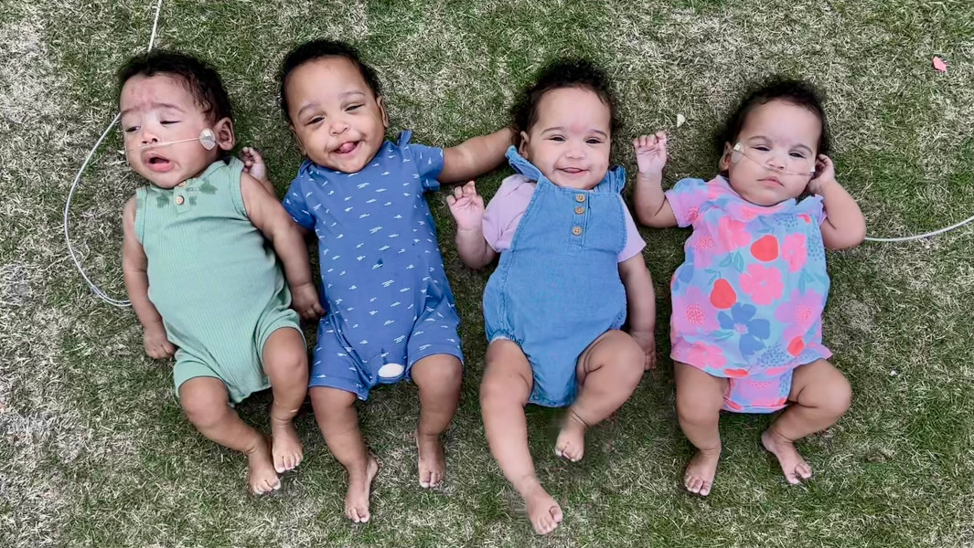 The Bryant quads smiling in the grass