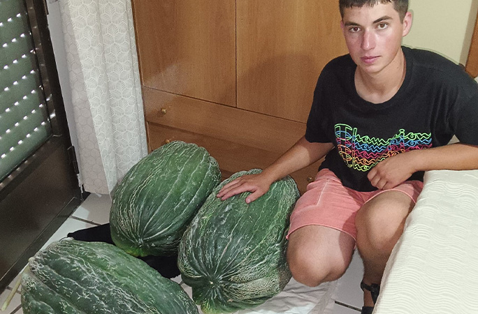 record holder posing with three big cantaloupes