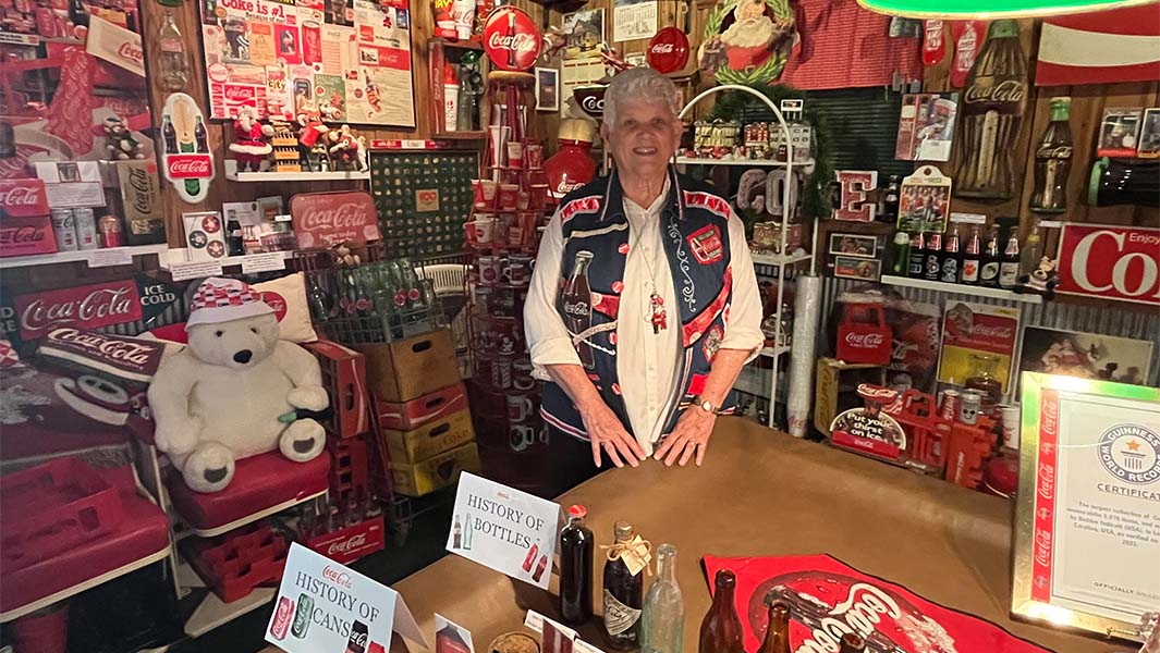 Debbie standing in her basement filled with Coca-Cola memorabilia