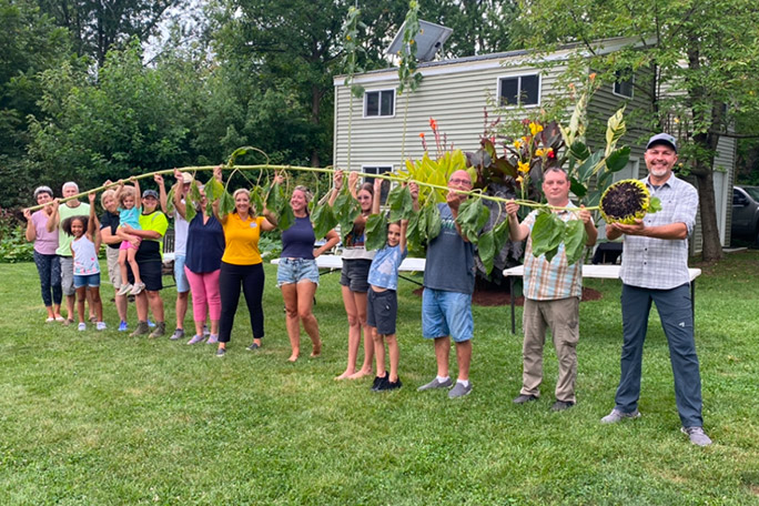 alex-babich-with-family-and-friends-holding-one-of-his-20-foot-plus-sunflowers-in-2024