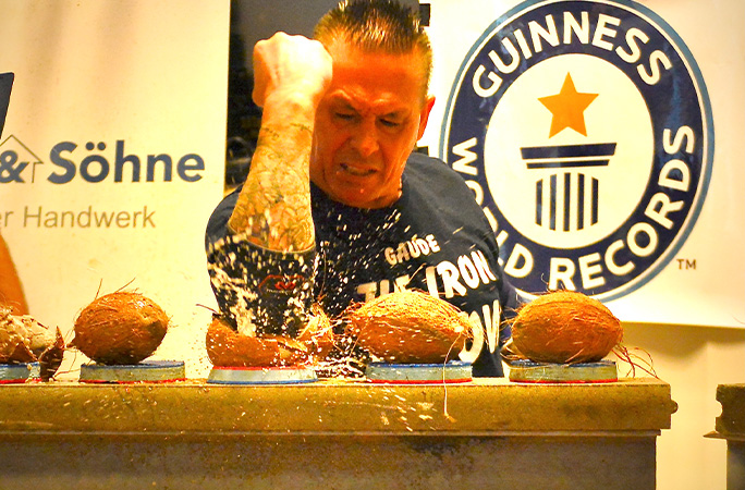 man smashing coconuts with his elbows