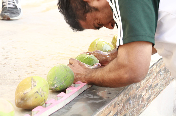 man smashing coconuts with his head
