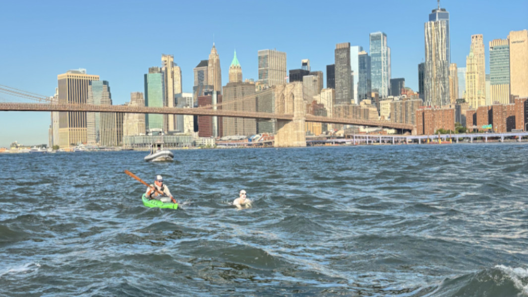 Michael Moreau swimming in front of the Manhattan skyline