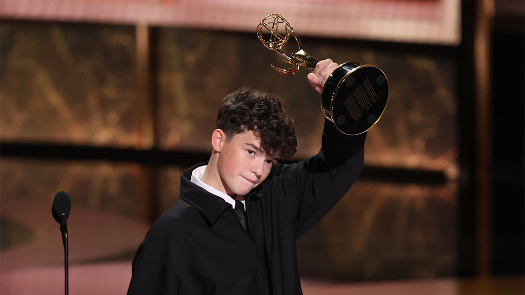 Owen Cooper lifting his Emmy Award in the air