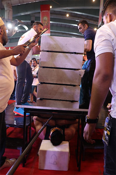 Vispy on a bed of nails with concrete blocks being broken on top of him