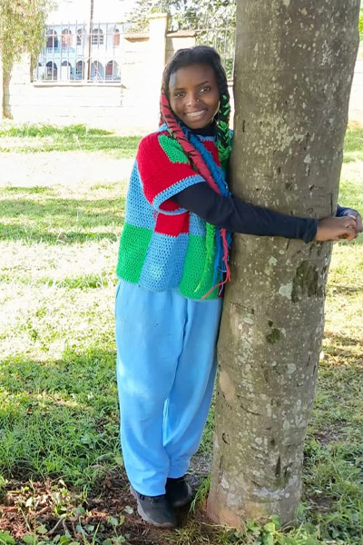 Truphena smiling while hugging a tree
