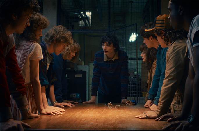 Stranger Things scene of the gang all standing round a table