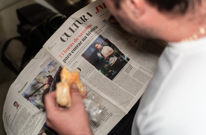 Elvis reading the newspaper and eating a donut