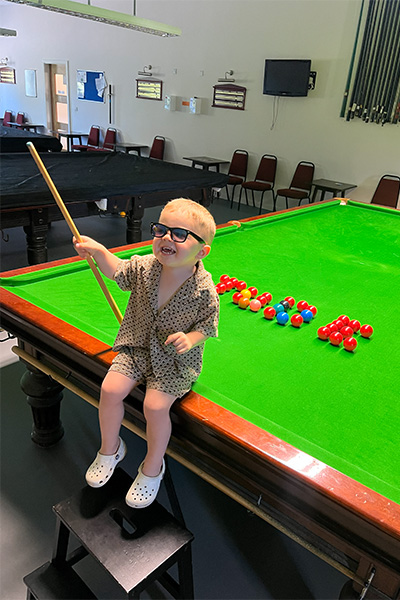 Jude sitting on table holding a cue