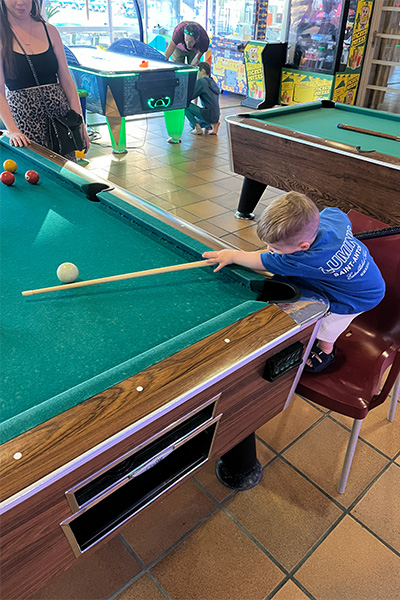 Jude standing on a chair playing pool
